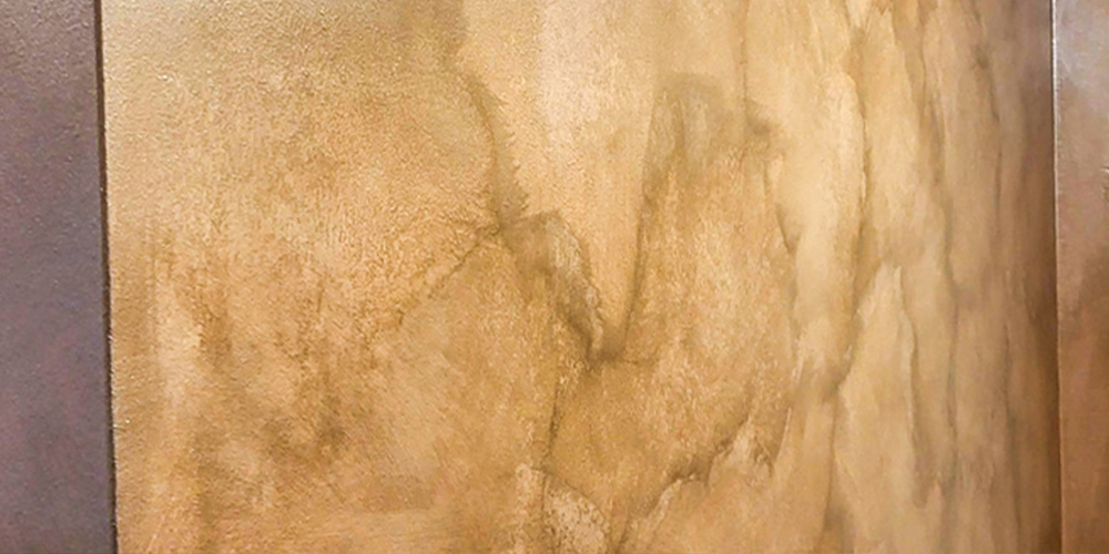 Braun-goldener Warnputz marmoriert. Das Licht der Decke spiegelt sich in der Wand.