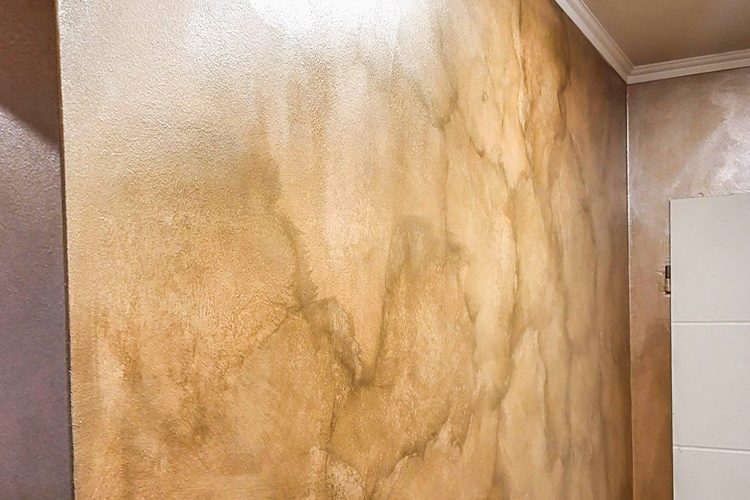 Wandputz goldbraun marmoriert, Lichtreflexe spiegeln sich in der Wand